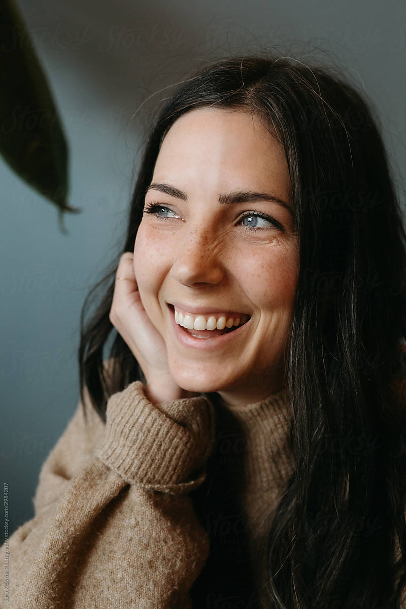 A woman smiling softly in warm daylight.